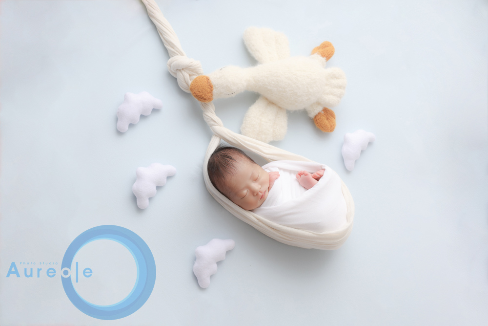 夫婦二人で新生児を囲み、丁寧に撮影準備をしている様子。