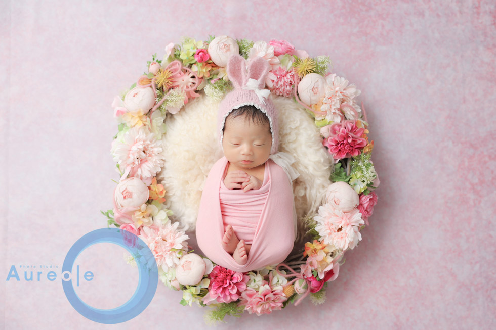花々に囲まれ穏やかに眠る新生児。